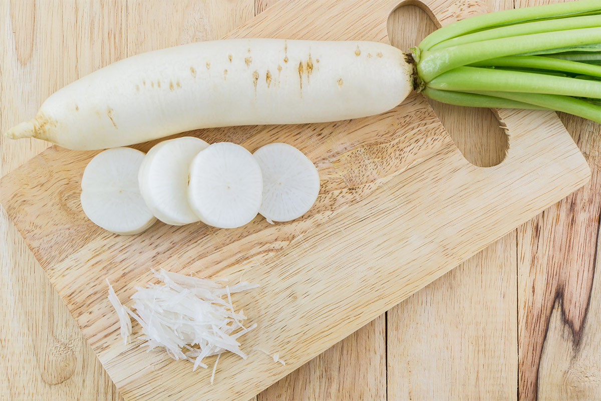 Daikon radish with a few slices and a grated piece are on a cutting board | Girl Meets Food