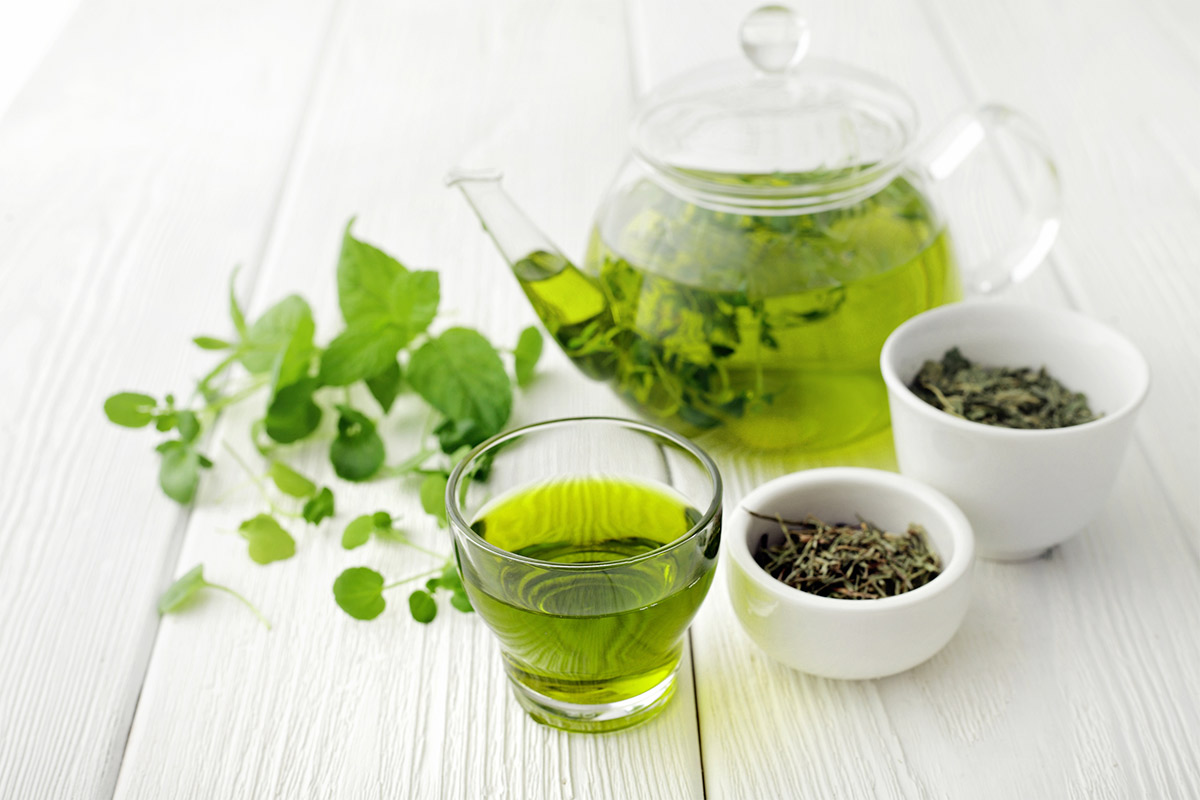 Green tea is ready in a transparent teapot and and a cup. There are 2 small bowls with tea next to them | Girl Meets Food