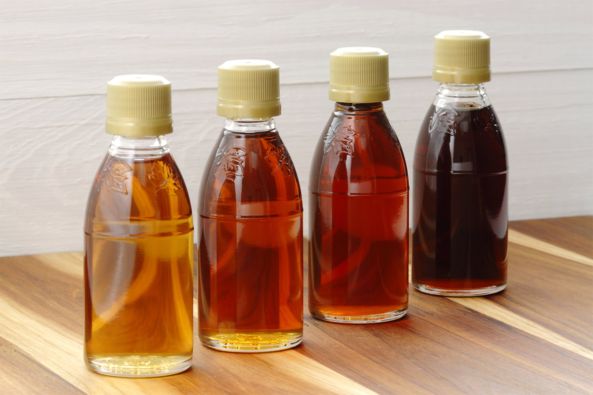 4 bottles of maple syrup stand on a wooden surface | Girl Meets Food