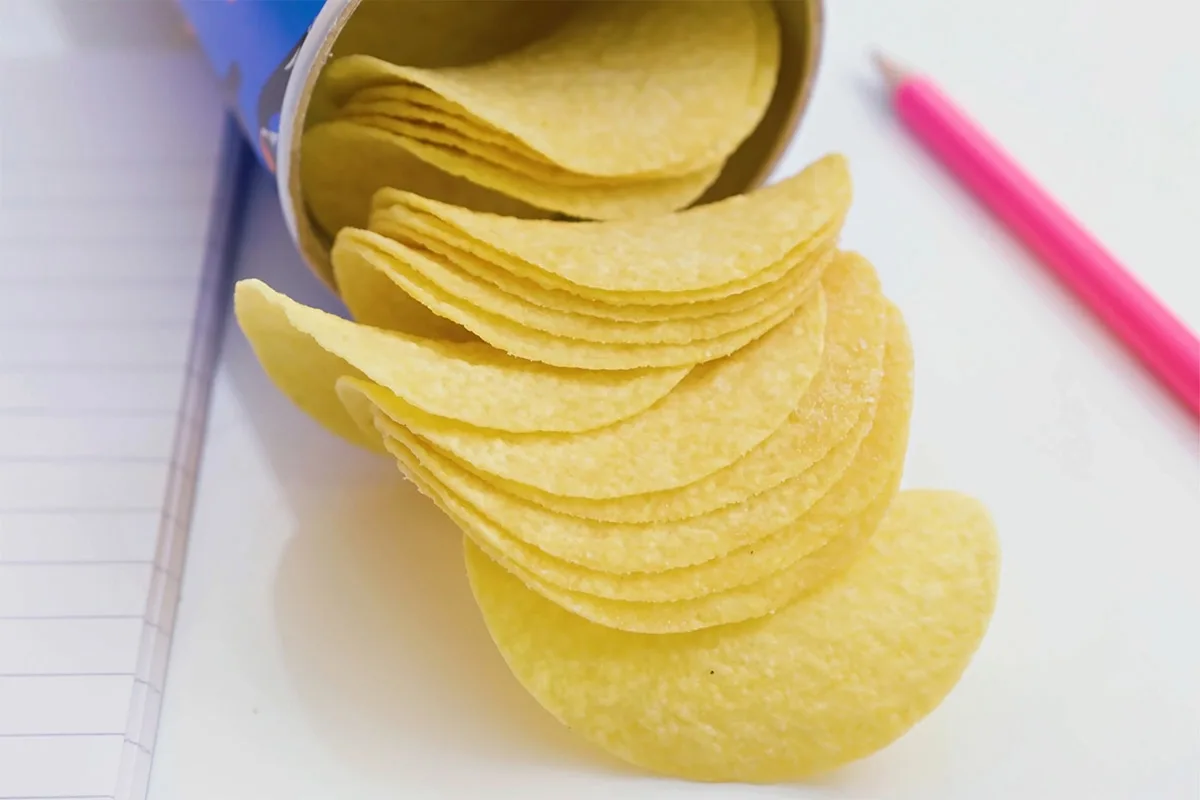 Chips are poured from the pack on the white surface | Girl Meets Food