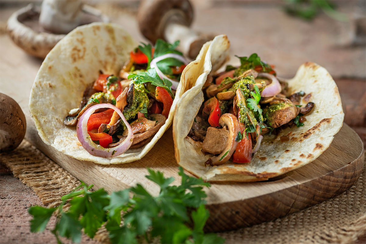 Vegan mushroom tacos are laid out on a wooden board | Girl Meets Food