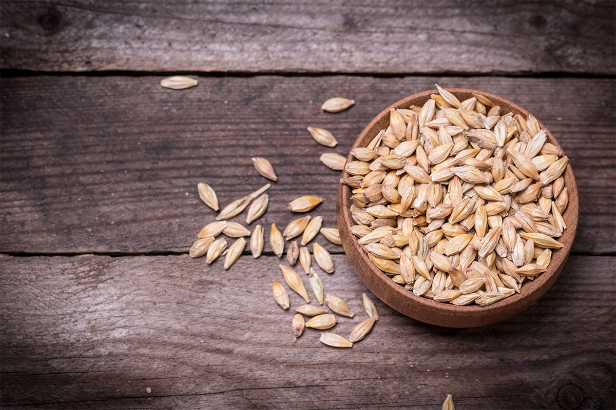 Wooden bowl with barley stands on a black wooden surface | Girl Meets Food