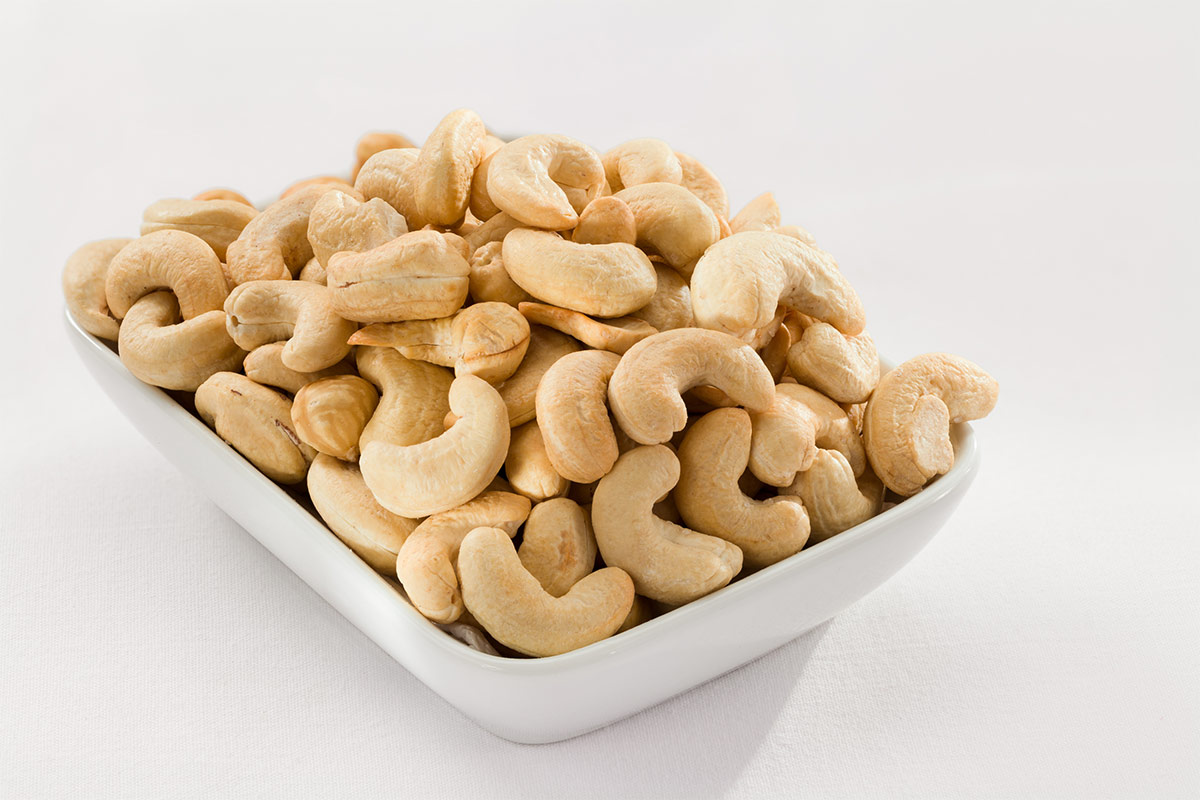 A white rectangle plate of cashews stands on a white surface | Girl Meets Food