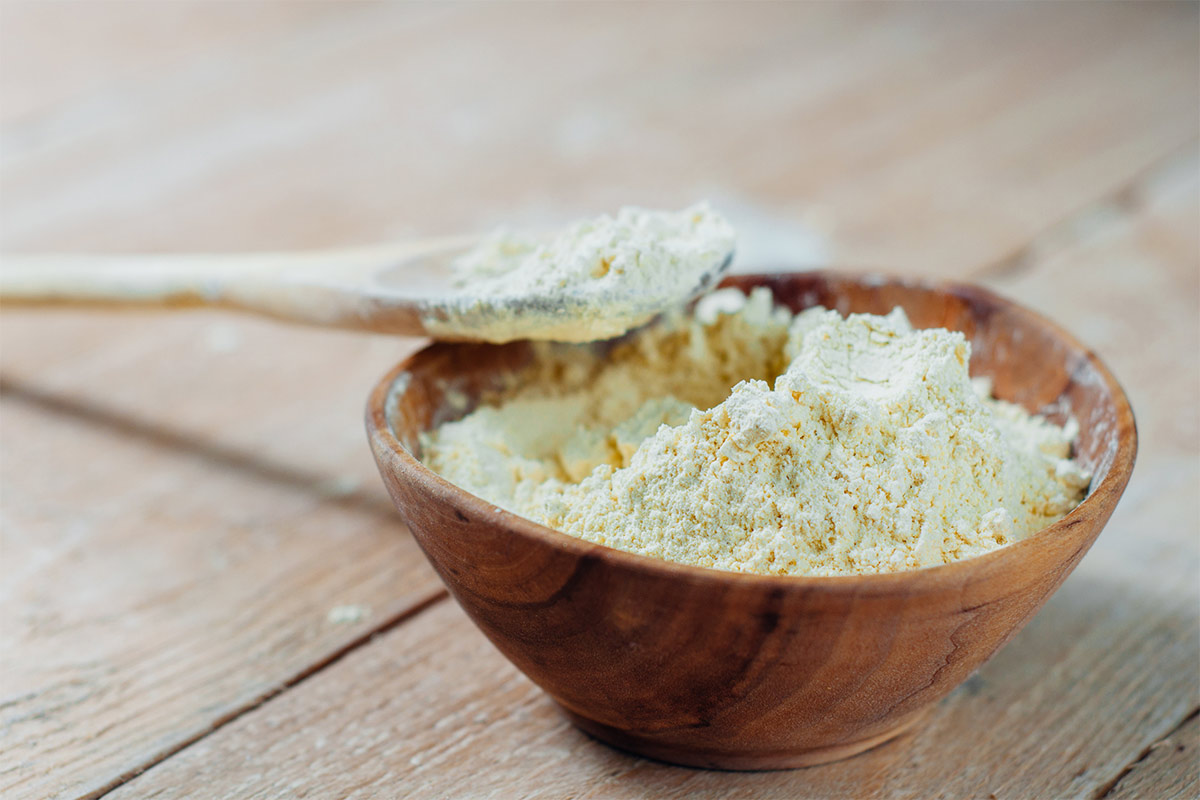 A wooden bowl of chickpea flour stands on a wooden surface | Girl Meets Food