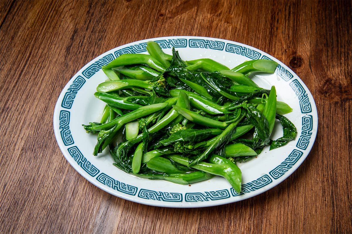A plate of sauteed Chinese broccoli lies on a table | Girl Meets Food