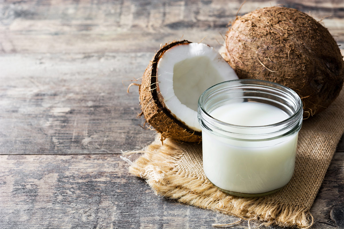 A jar of coconut milk, a coconut and a half stand on a linen cloth | Girl Meets Food