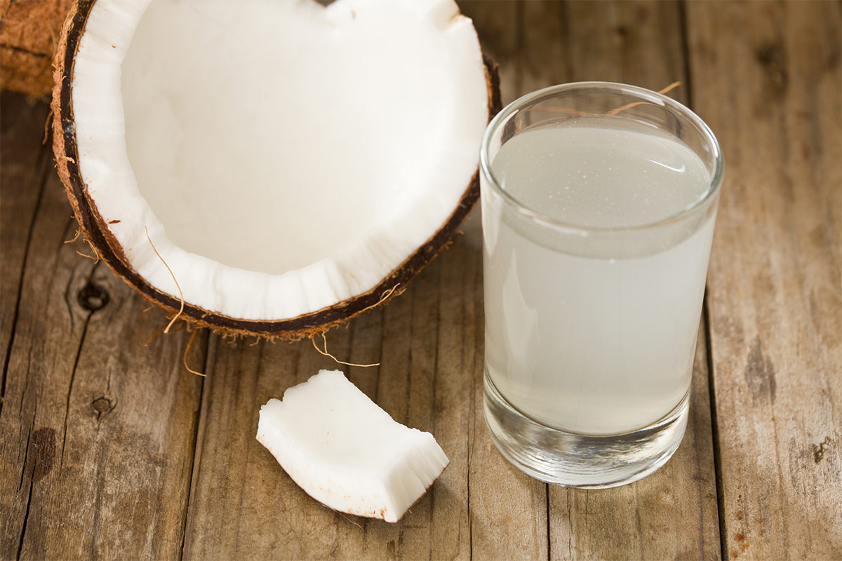 A glass of coconut water stands together with half of coconut | Girl Meets Food