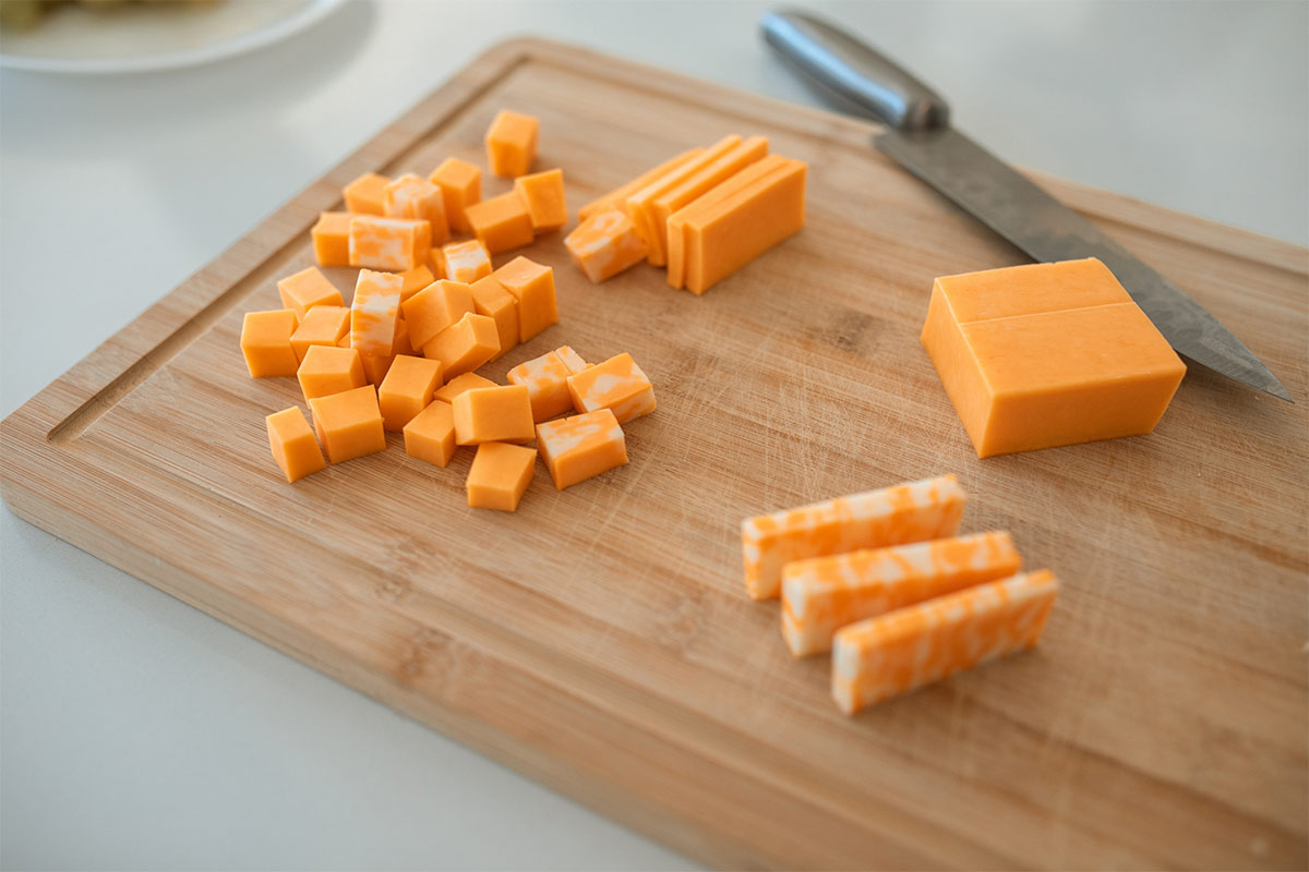 Colby cheese cubes with a knife lie on a cutting board | Girl Meets Food