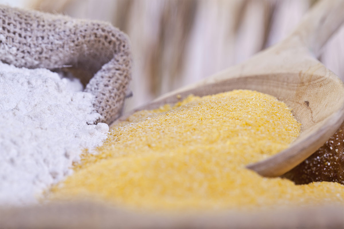 A sack of wheat flour next to a wooden spoon of cornmeal | Girl Meets Food