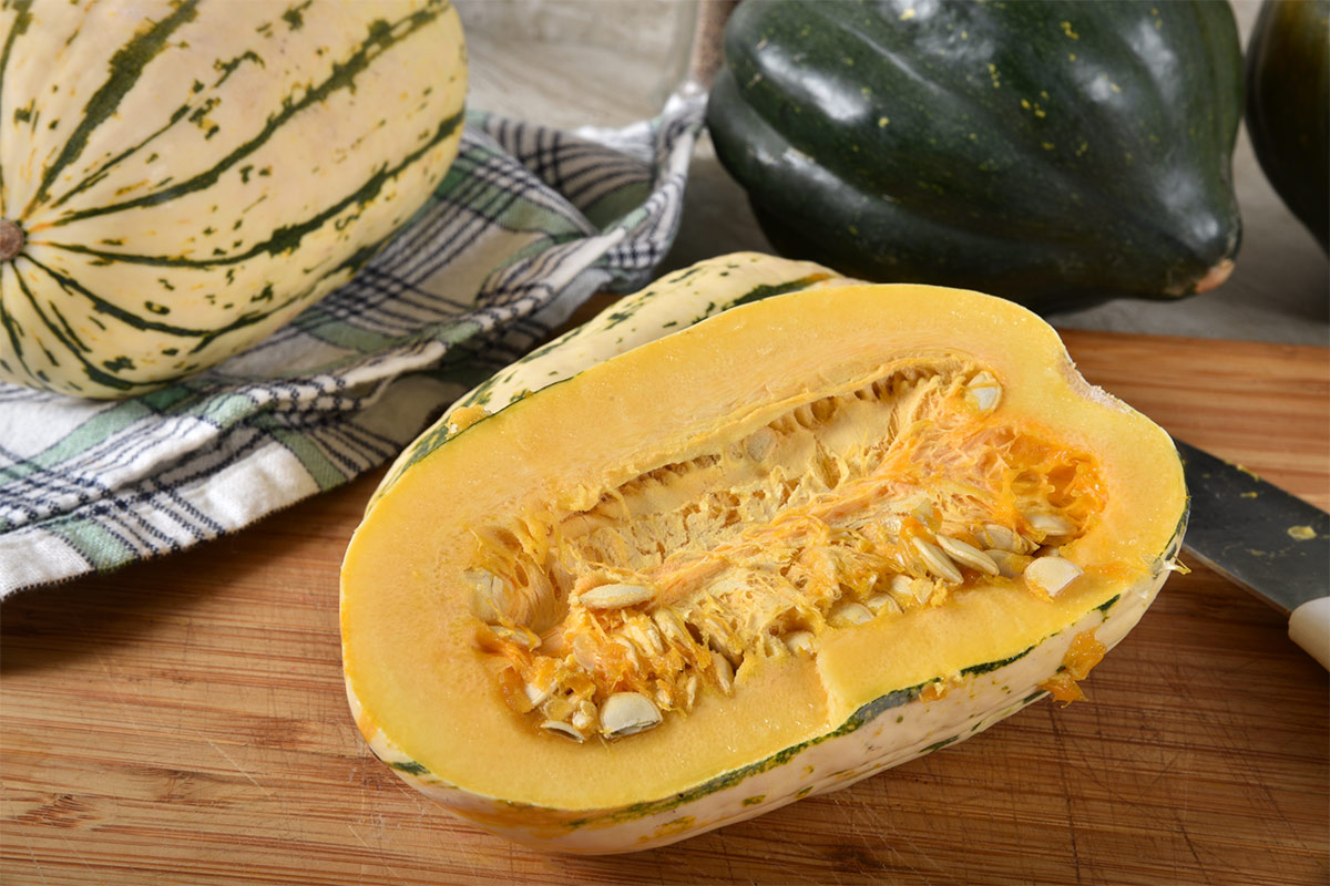 There is a half of delicata squash on a table and a few other pieces on the background | Girl Meets Food