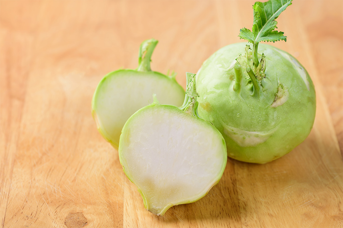 One kohlrabi and two halves lie on a wooden surface | Girl Meets Food