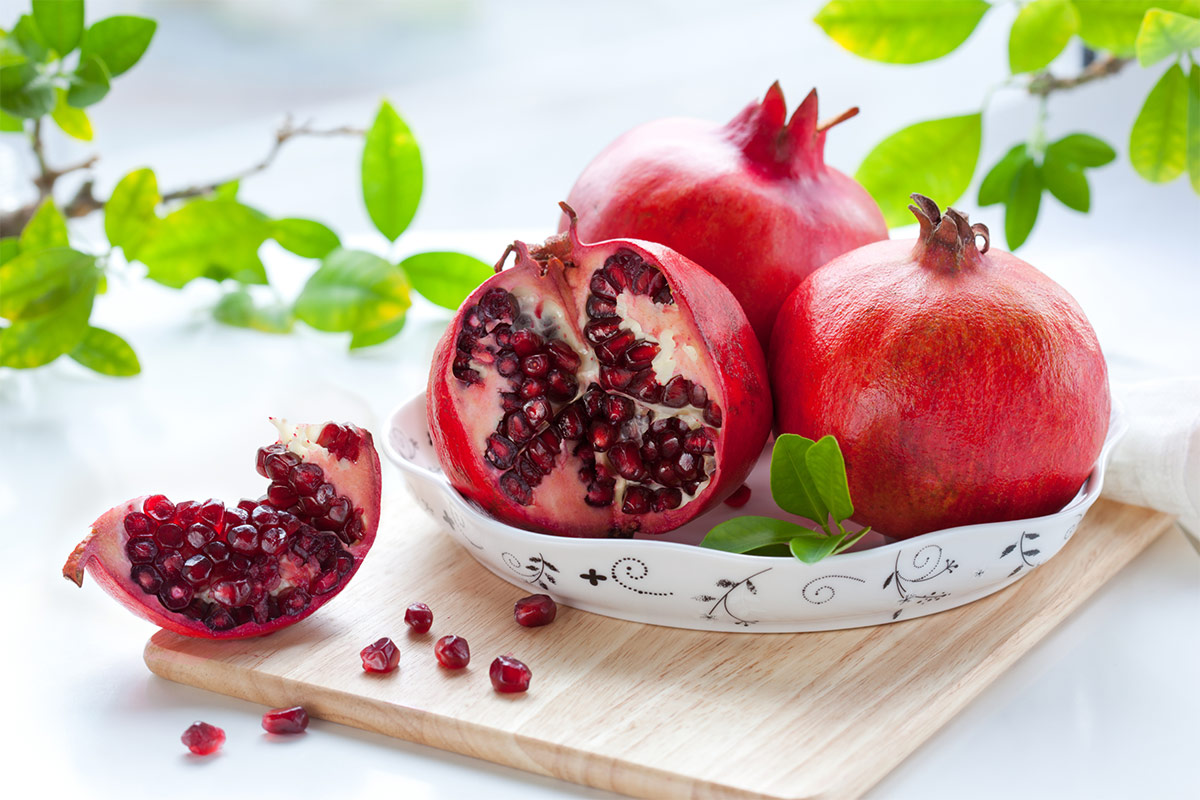 A white plate with pomegranates is on a wooden board | Girl Meets Food