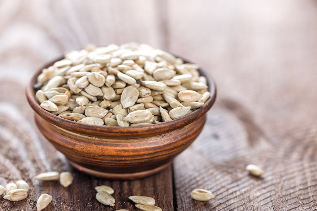 A bowl full of sunflower seeds on a wooden bowl | Girl Meets Food