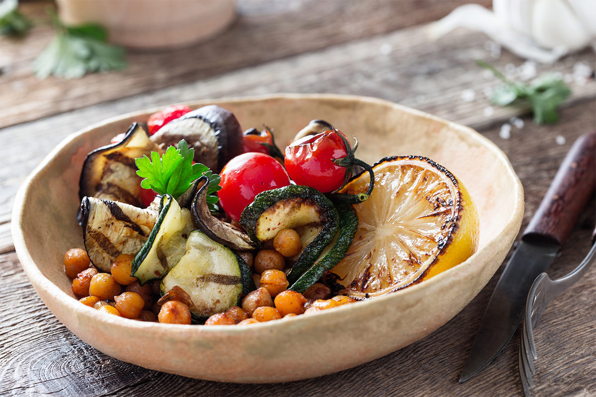 A bowl of grilled vegetables stands on a table | Girl Meets Food