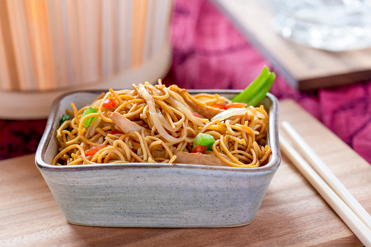 Chow Mein in a square bowl with chopsticks lie on a table | Girl Meets Food