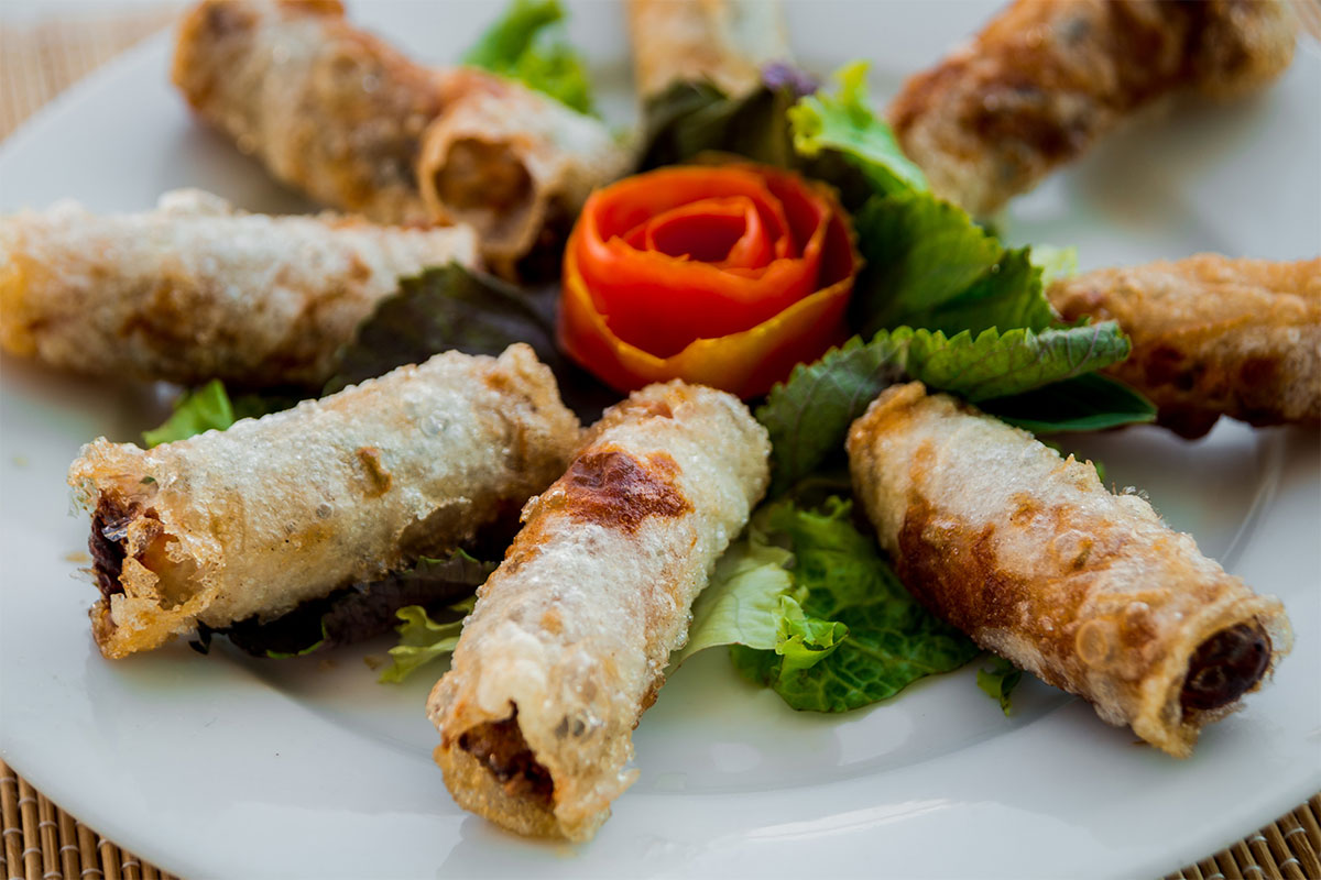 A plate of egg rolls with salad leaves on a table | Girl Meets Food