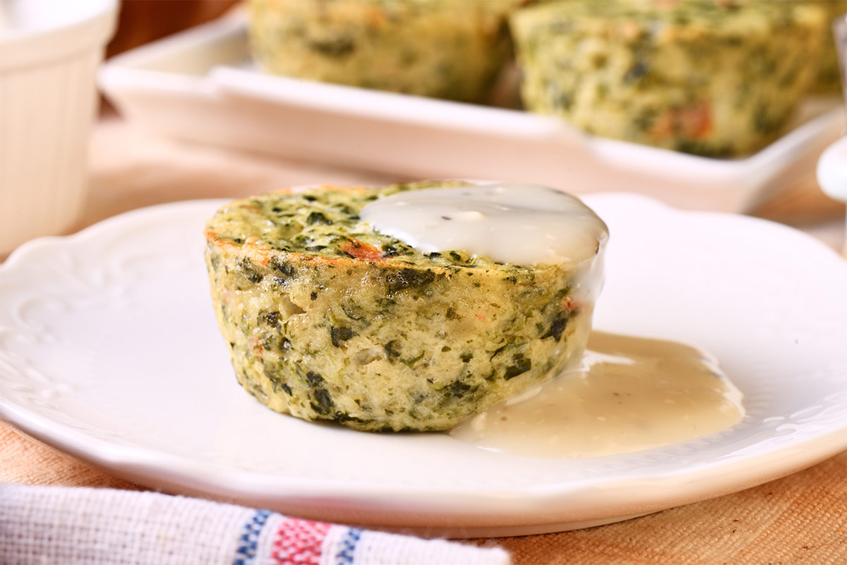Spinach frittata topped with white sauce is on a plate that is on the table | Girl Meets Food