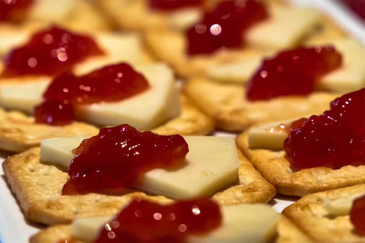 Several crackers topped with Manchego cheese slices and jam | Girl Meets Food