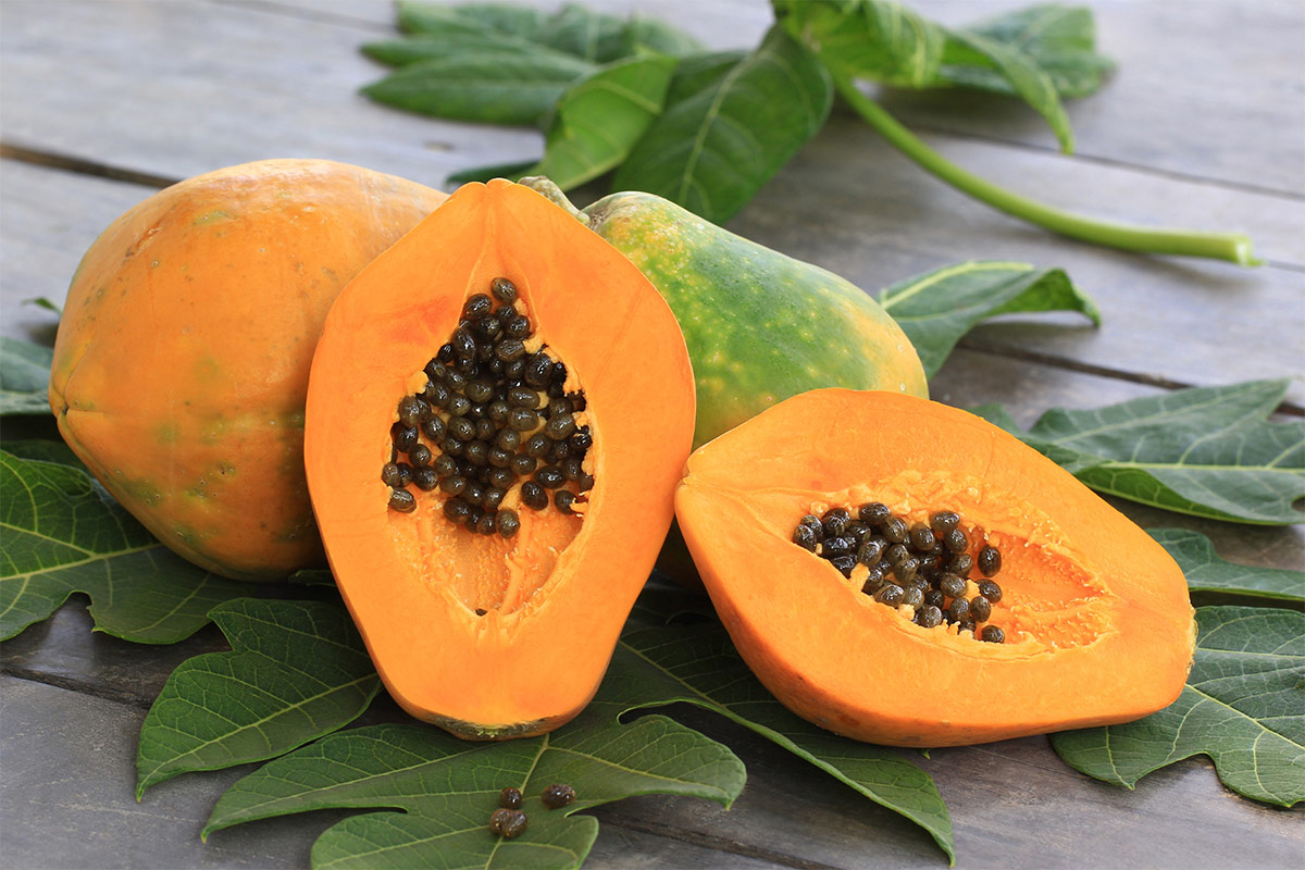 A few papayas lie on leaves on a table | Girl Meets Food