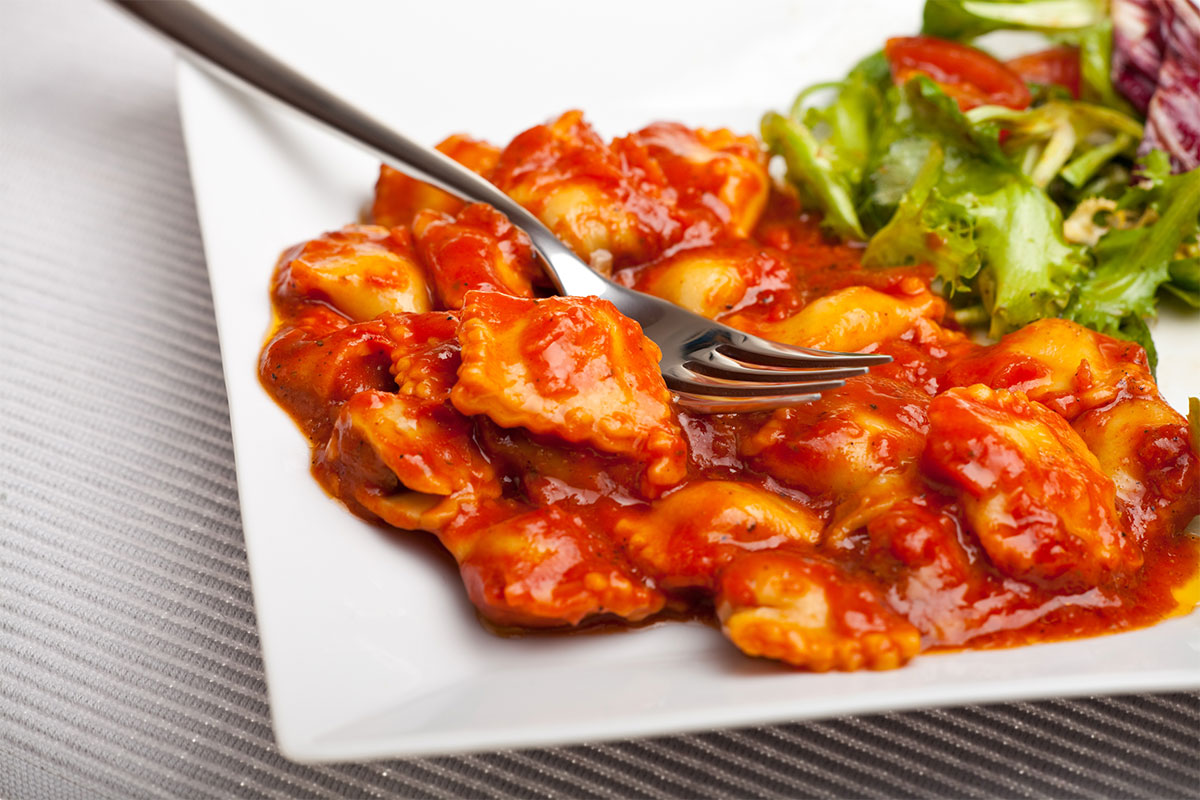 A white plate of tomato ravioli with salad | Girl Meets Food