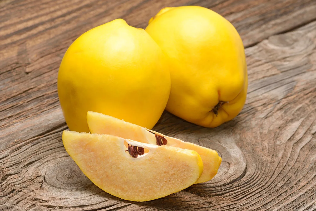 Two quinces and two quince wedges are on a wooden surface | Girl Meets Food