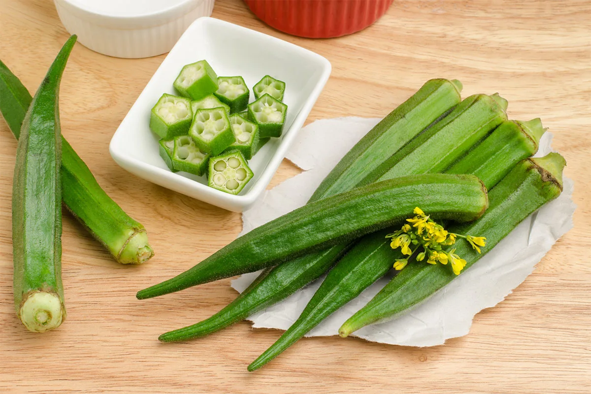 Fresh okra on a table and okra slices in a rectangle bowl | Girl Meets Food