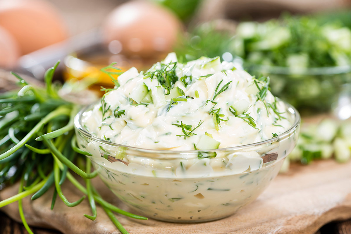 A small transparent bowl with remoulade sauce on a table. There are some green next to it | Girl Meets Food