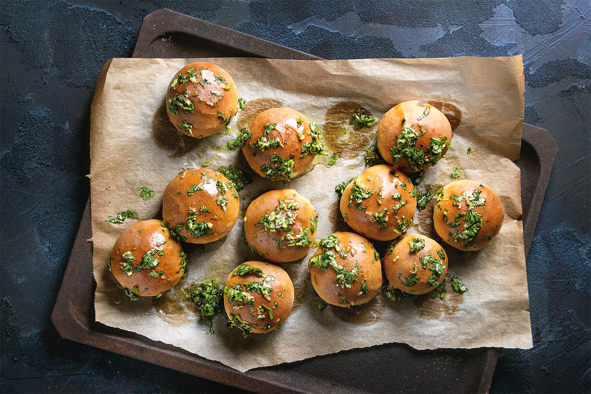 Ukrainian garlic pampushky on a parchment paper that is on a baking tray | Girl Meets Food