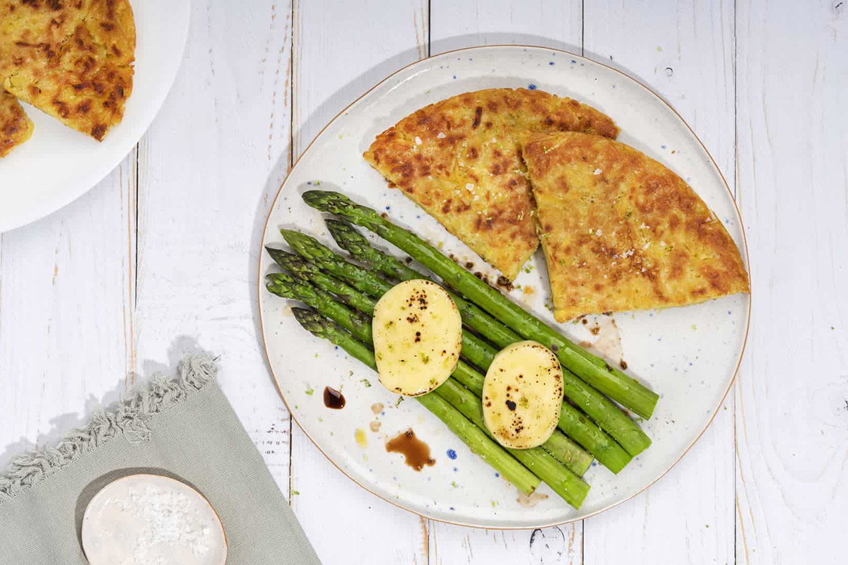 A plate of rosti and asparagus on a white wooden surface | Girl Meets Food