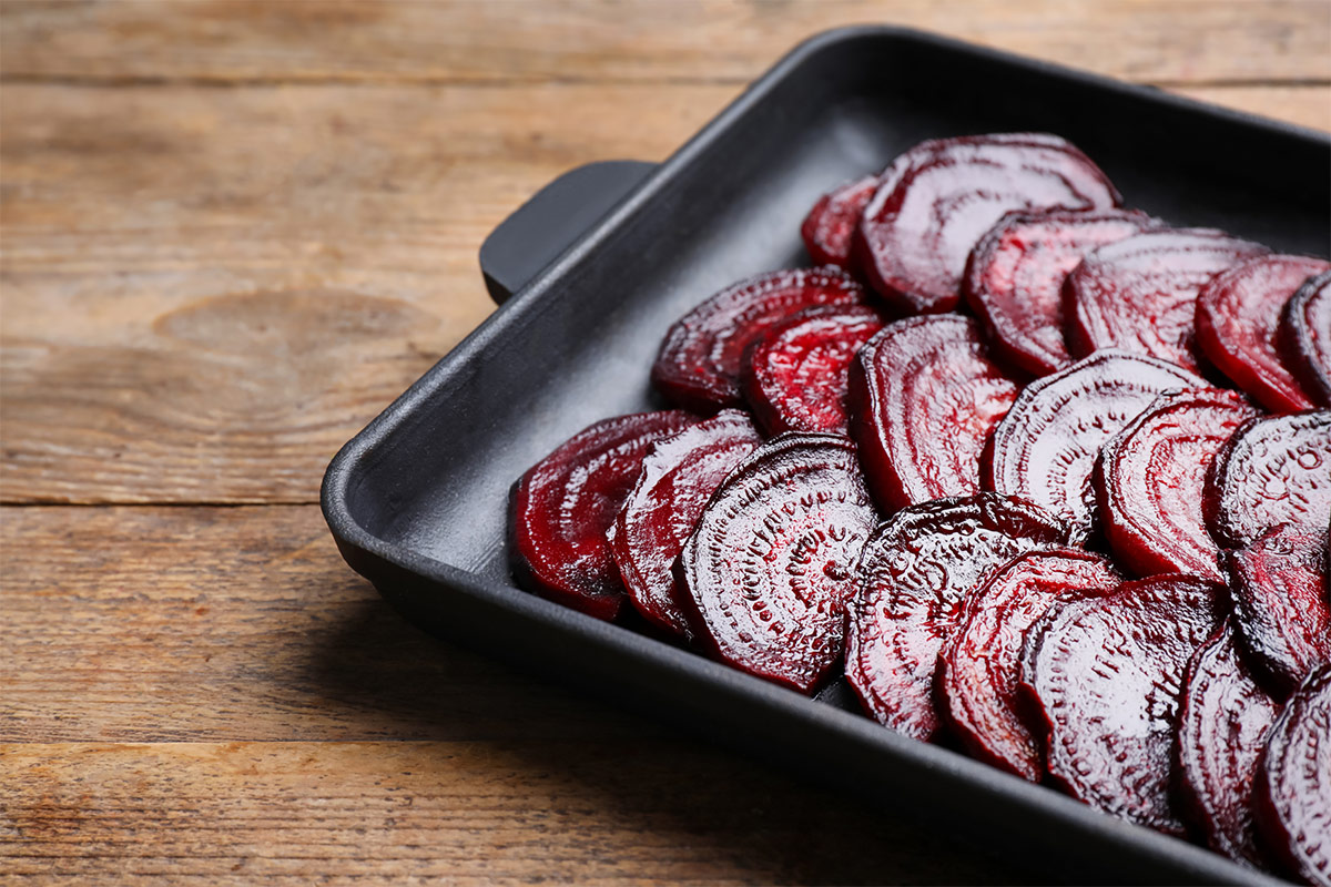Baking dish with roasted beetroot slices on wooden table | Girl Meets Food