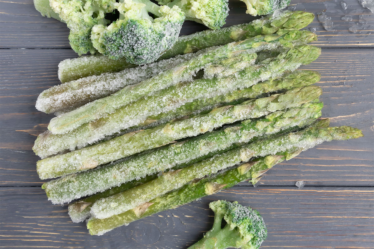 Frozen asparagus and broccoli on wooden surface | Girl Meets Food