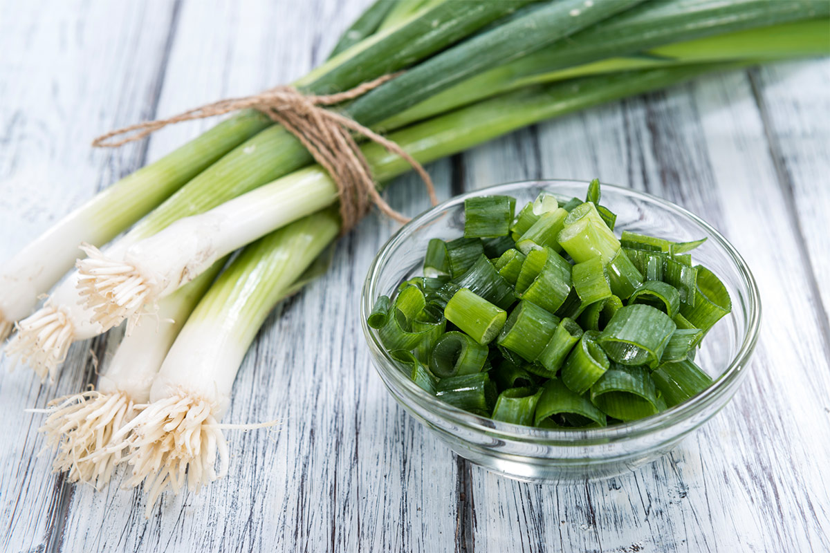 Scallions with a bowl of chopped scallion on wooden surface | Girl Meets Food