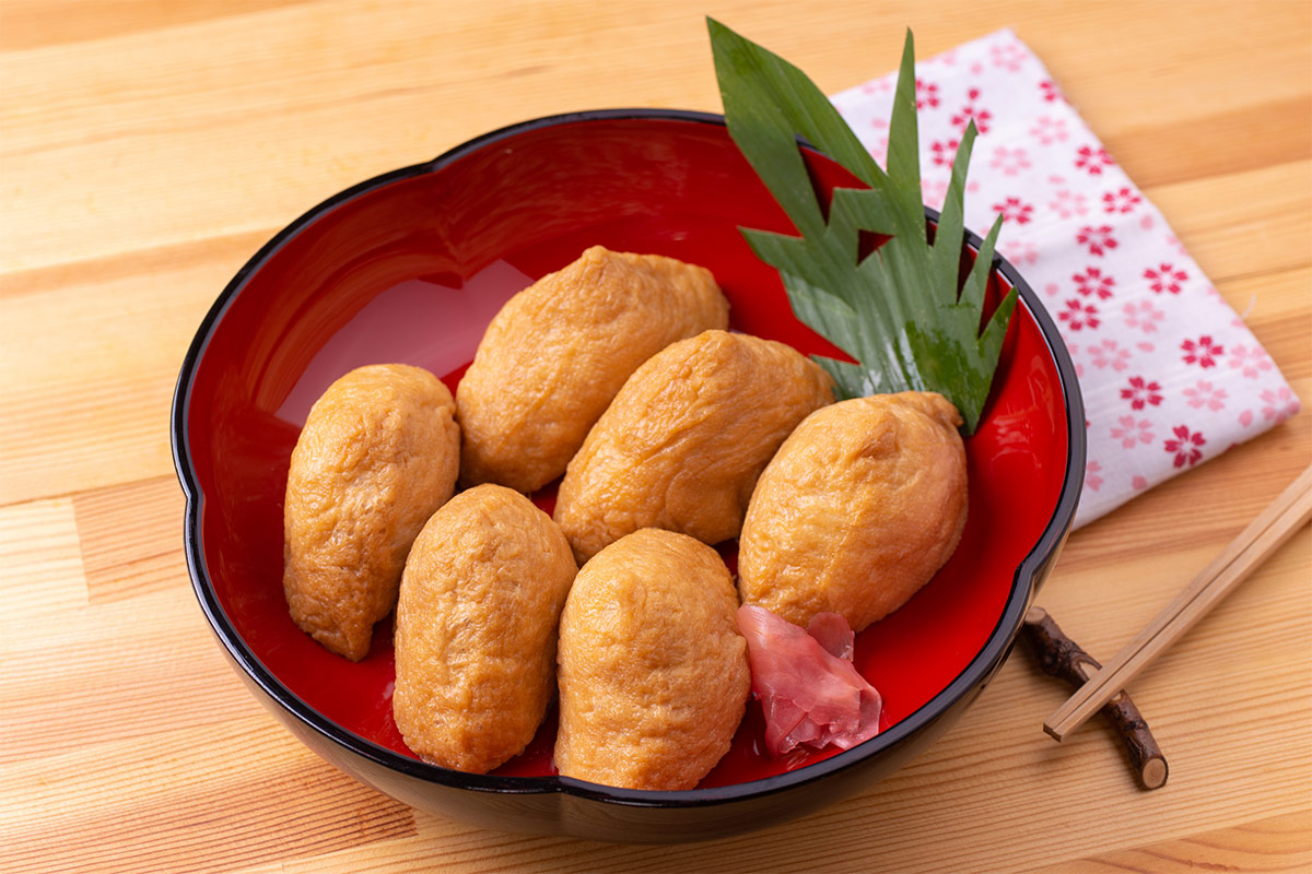 Yubuchobap (Inari Sushi) in a red bowl that is on a table | Girl Meets Food