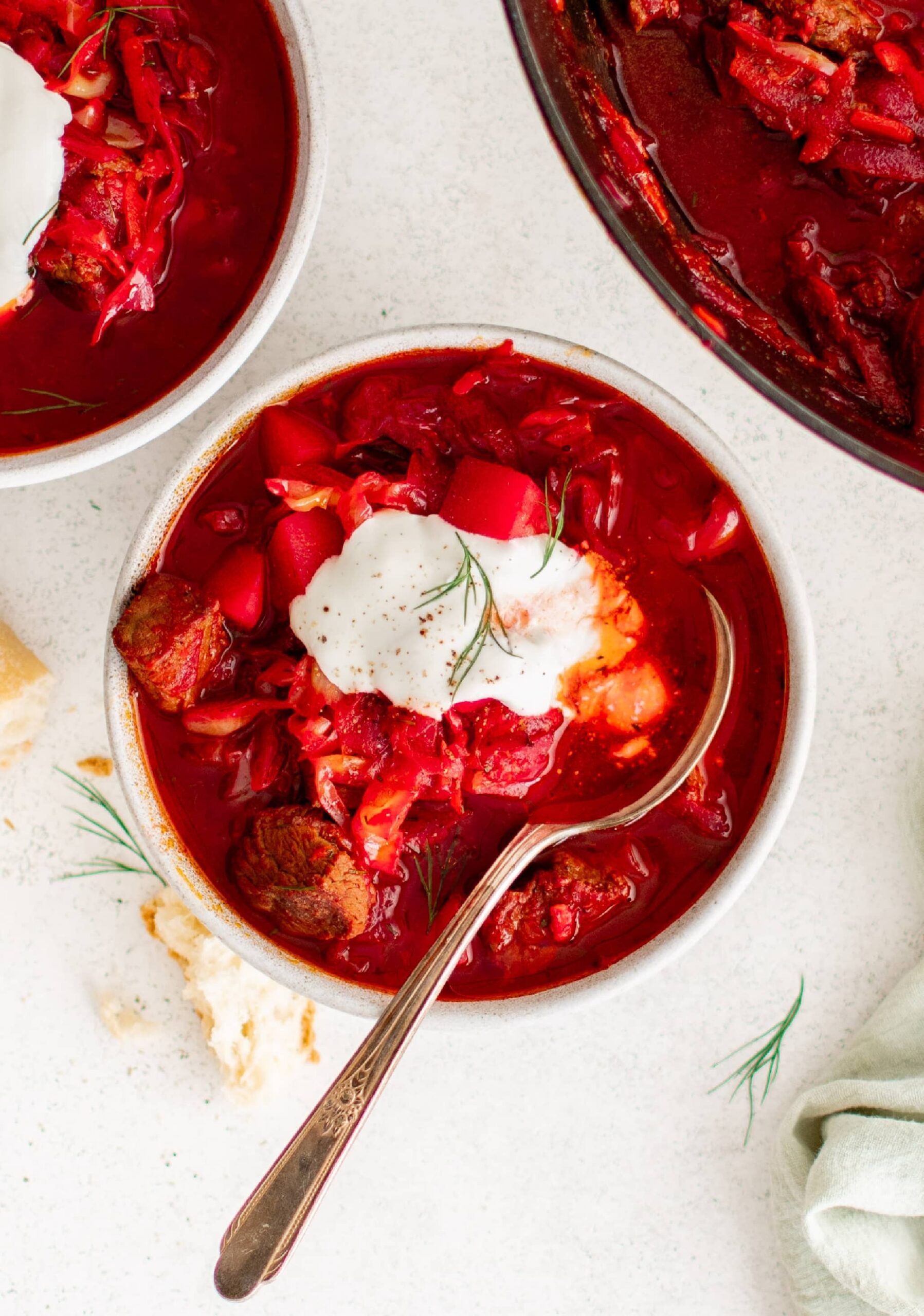 A bowl of borscht soup topped with sour cream on the table | Girl Meets Food