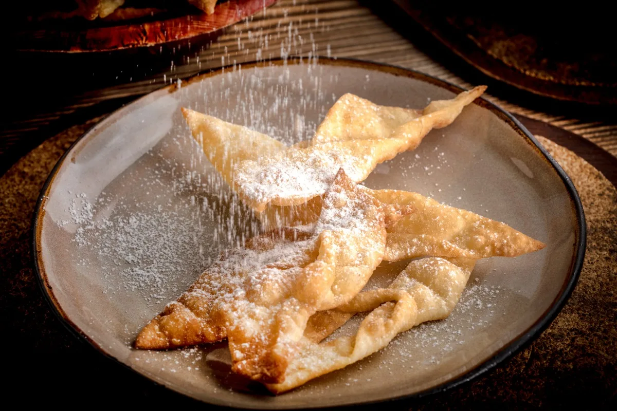 A plate of Faworki decorated with powdered sugar | Girl Meets Food