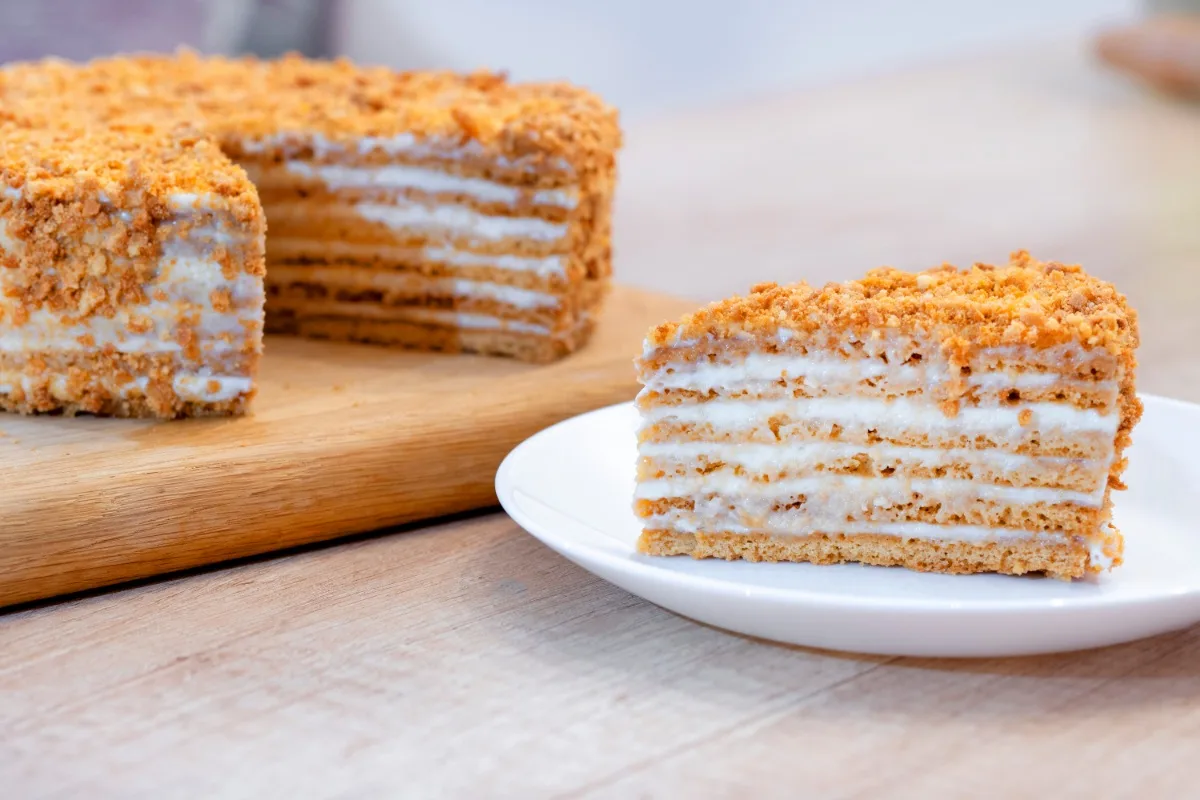 Medus Kūka (Honey Cake) on a cutting board. A plate with a piece of cake next to it | Girl Meets Food