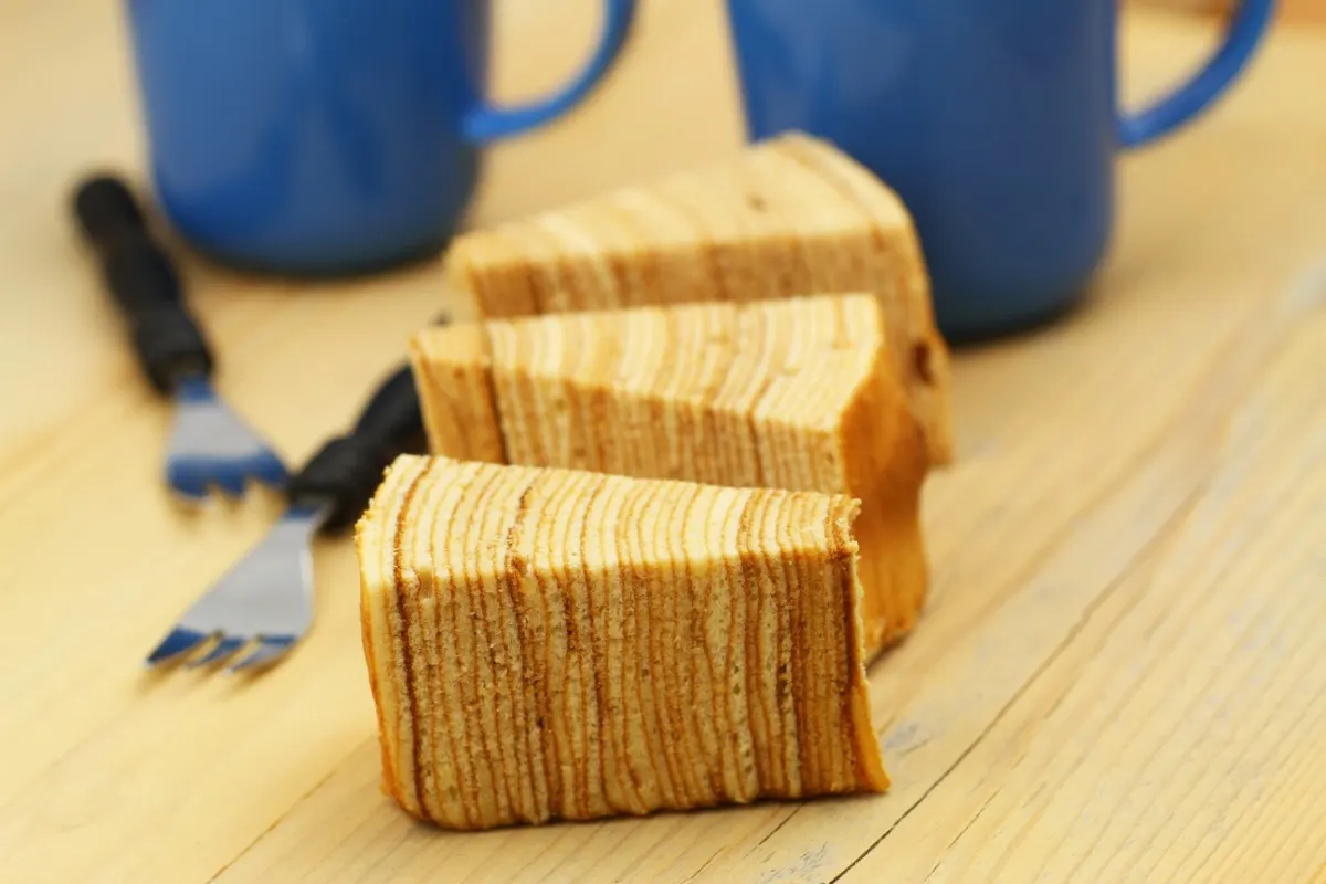 Three pieces of Sekach (Polish cake) on a table. There are two forks and two cups next to them | Girl Meets Food