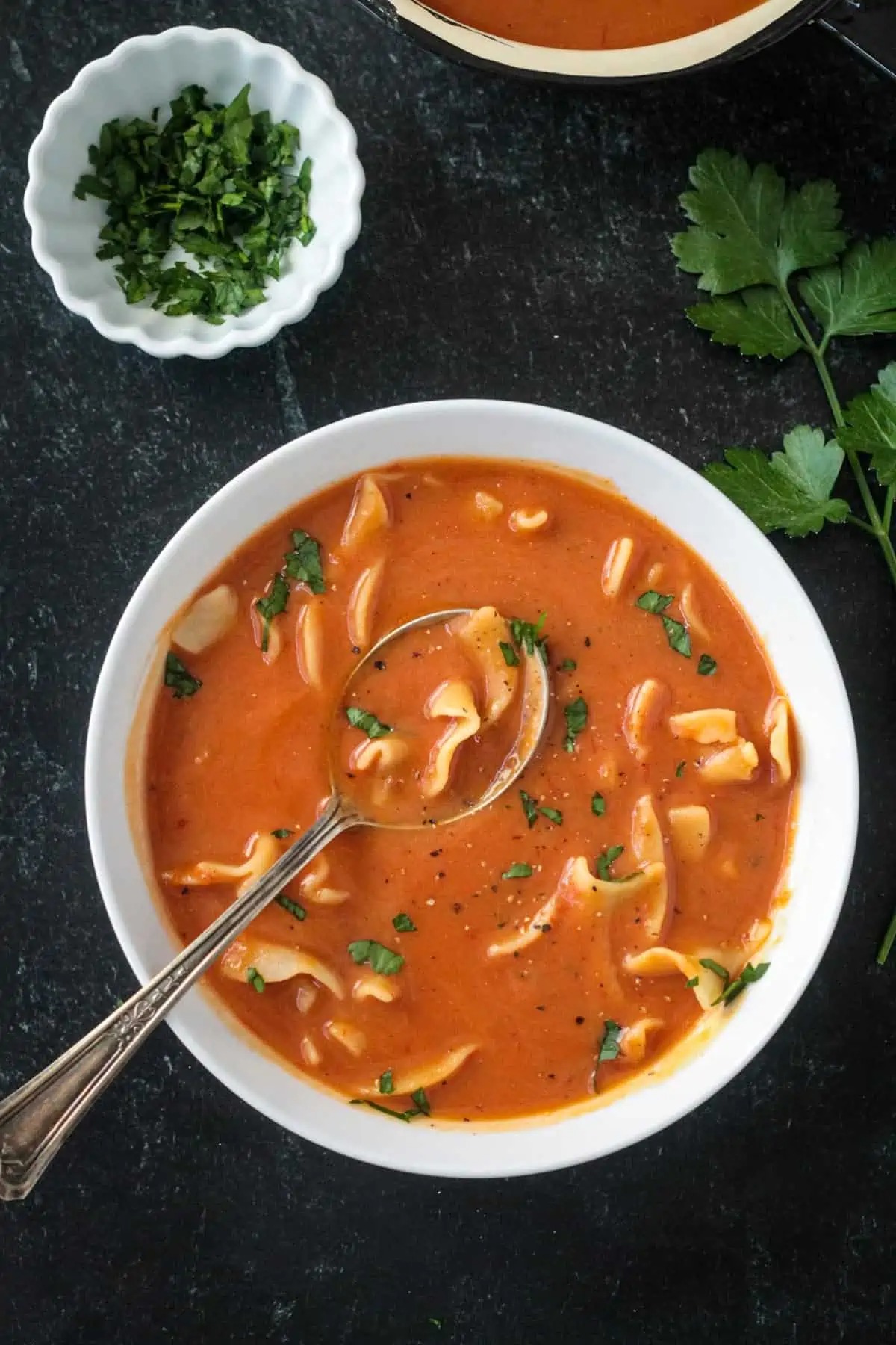 A bowl of Polish tomato soup and chopped parsley on the black surface | Girl Meets Food