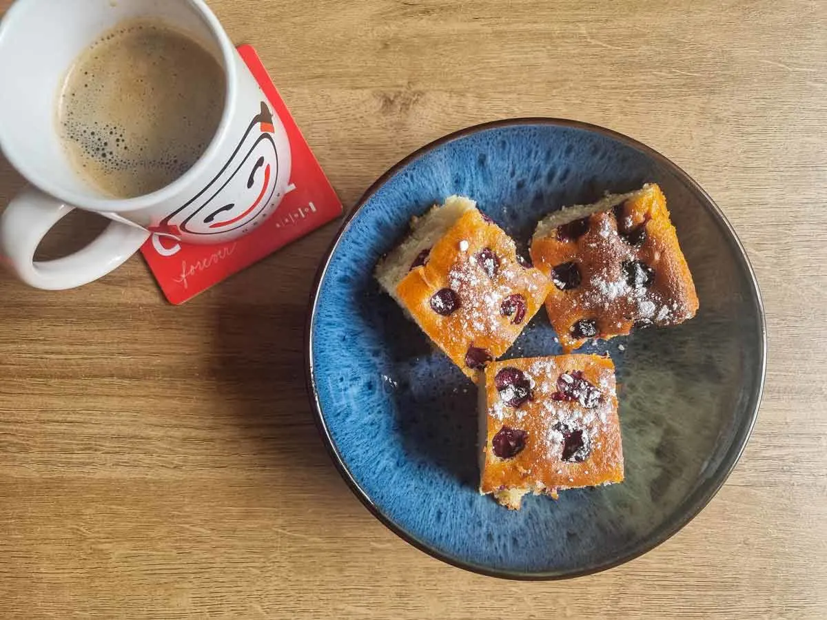 A blue plate with 3 pieces of Romanian cherry cake and a cup of coffee on the table | Girl Meets Food