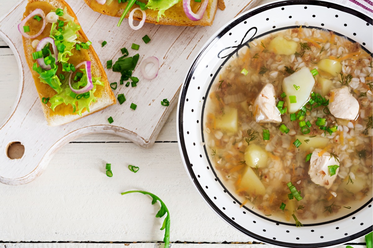 A bowl of buckwheat soup on the table. Bread toasts with greens are next to the bowl | Girl Meets Food