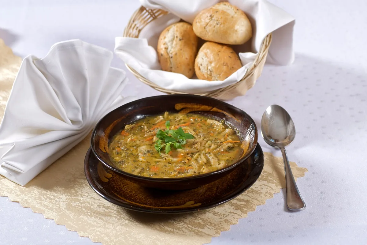 A bowl of flaki on the table. A wicker basket with buns is next to the bowl | Girl Meets Food