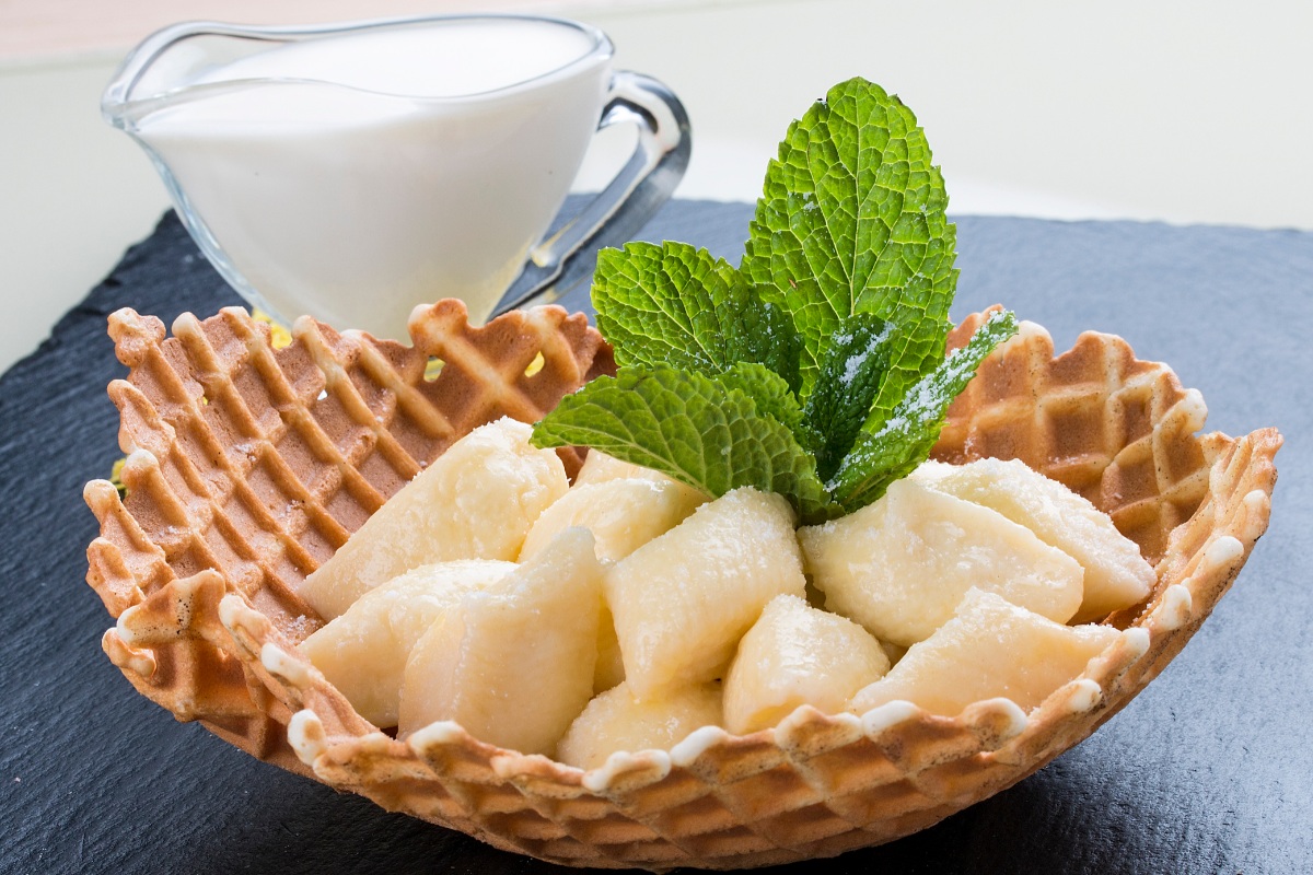 Leniwe Pierogi in a waffle bowl topped with powdered sugar and mint leaves | Girl Meets Food